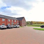 Brick houses with parked cars in countryside setting.