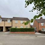 Semi-detached house with hedge and driveway.