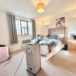 Spacious bedroom with bed, desk, and air cooler.