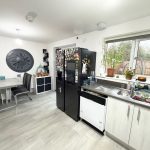 Modern kitchen with large wall clock and plants.