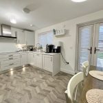 Modern kitchen with white cabinets and patio doors.