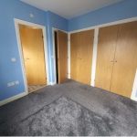 Empty blue carpeted room with wooden doors.