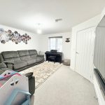Living room with sofas, wall photos, and piano.