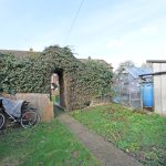 Garden with bike, greenhouse, and ivy-covered archway.