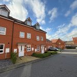 Modern red brick terraced houses on residential street.