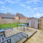 Modern garden with decking, furniture, and shed.