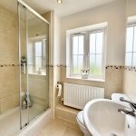 Modern bathroom with shower, sink, and window.