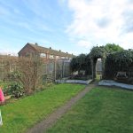 Back garden with path, benches, and pink umbrella.
