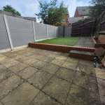 Paved garden with grass area and fences.