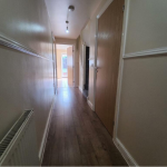 Long hallway with wooden floor and doors.