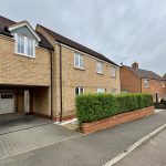 Modern UK brick house with driveway and hedge.