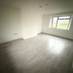 Empty room with wooden floor and large window.