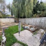 Back garden with lawn, gravel, and trees.