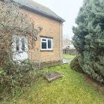 Brick house with white door and window; garden view.
