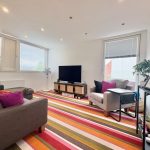 Modern living room with striped carpet and large windows.