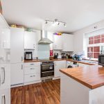 Modern kitchen with white cabinets and wooden countertops.