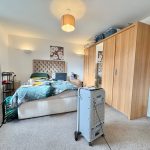 Spacious bedroom with modern decor and wooden wardrobe.
