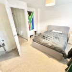Bedroom with grey bed, flag, and open door.