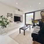 Modern living room with pinball machine and large plant.