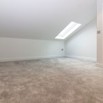 Empty room with skylight and wooden door.