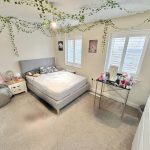 Cosy bedroom with grey bed and hanging plants.