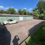 Vintage car parked near blue garages.