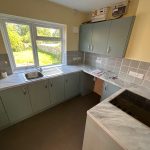 Modern kitchen with grey cabinets and garden view.