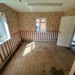 Empty room with wooden floor and patterned wallpaper.