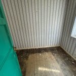 Old room with wallpaper and wooden floorboards.