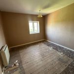 Empty room with wooden floor, small window, light fixture.