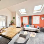 Modern kitchen with colourful sofa and skylights.