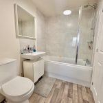Modern bathroom with toilet, sink, and bathtub.