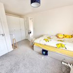 Bedroom with Pikachu bedding and white wardrobes.