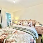 Cosy bedroom with floral bedding and mirrored wardrobe.