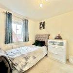 Bright bedroom with bed and chest of drawers.
