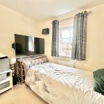 Cosy bedroom with TV and window view.