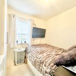 Small cosy bedroom with TV and window view.