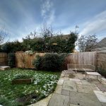 Back garden with patio and winter grass.