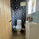 Stylish bathroom with floral wallpaper and modern fixtures.