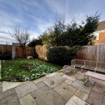 Back garden with patio, snow patches, and wooden fence.