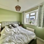 Bright bedroom with green walls and window view.