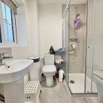 Modern bathroom with shower, sink, and toilet.