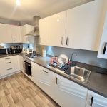 Modern kitchen with white cabinets and wooden floor.