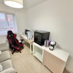 Gaming room with chair, console, and coffee machine.
