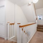 Bright hallway with carpeted stairs and white doors.