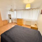 Spacious bedroom with wooden furniture and natural light.