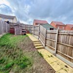 Fenced garden with shed and patio path.