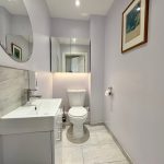 Modern bathroom with mirror, sink, and toilet.