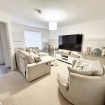 Modern living room with beige furniture and TV.