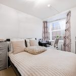 Modern bedroom with double bed and desk.